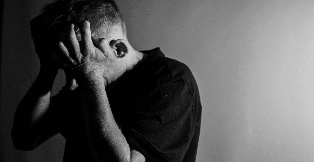 Um homem com as mãos sobre o rosto demonstrando frustração